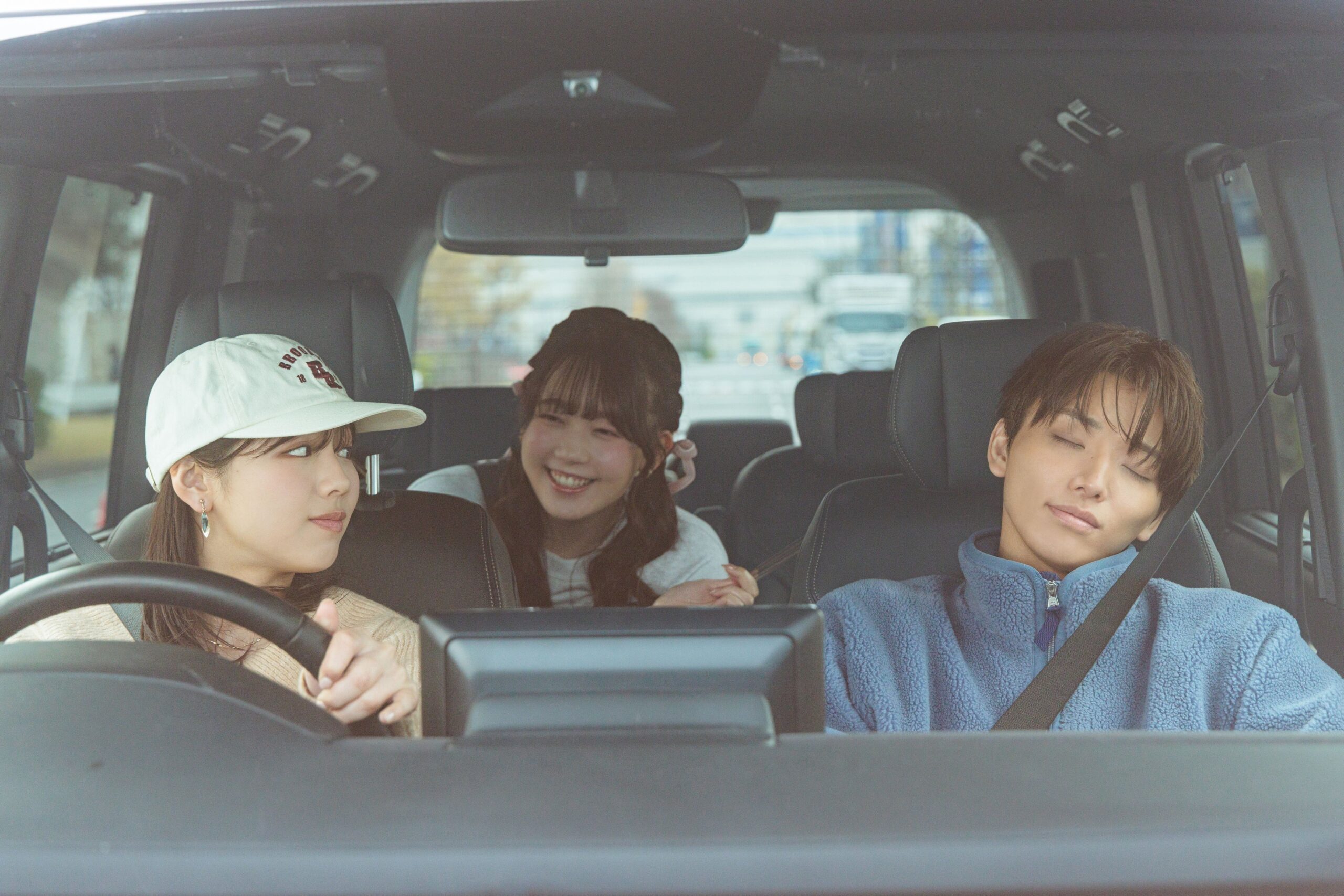 車内で眠る男性と運転中の女性たち