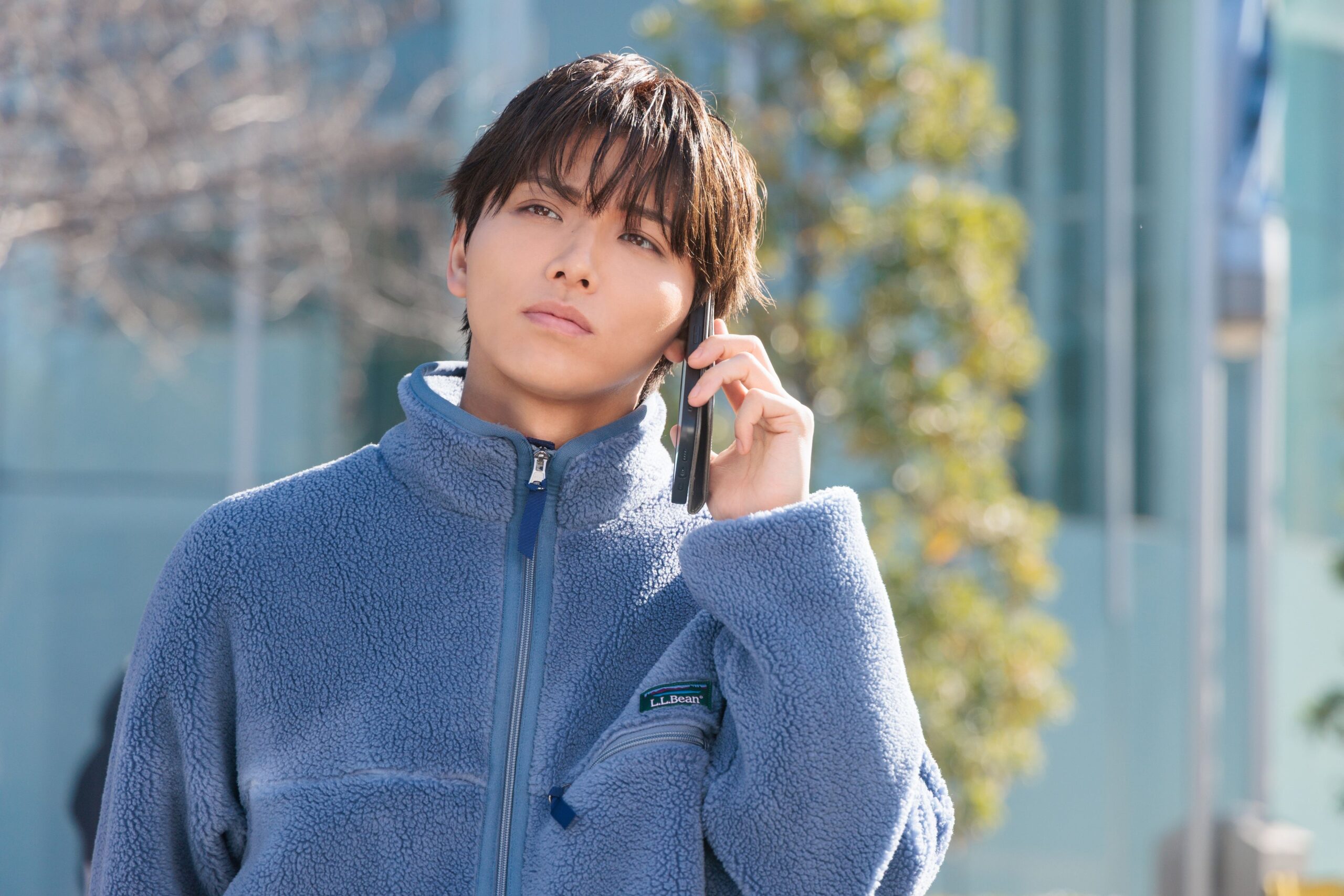 外で電話する青い上着の男性