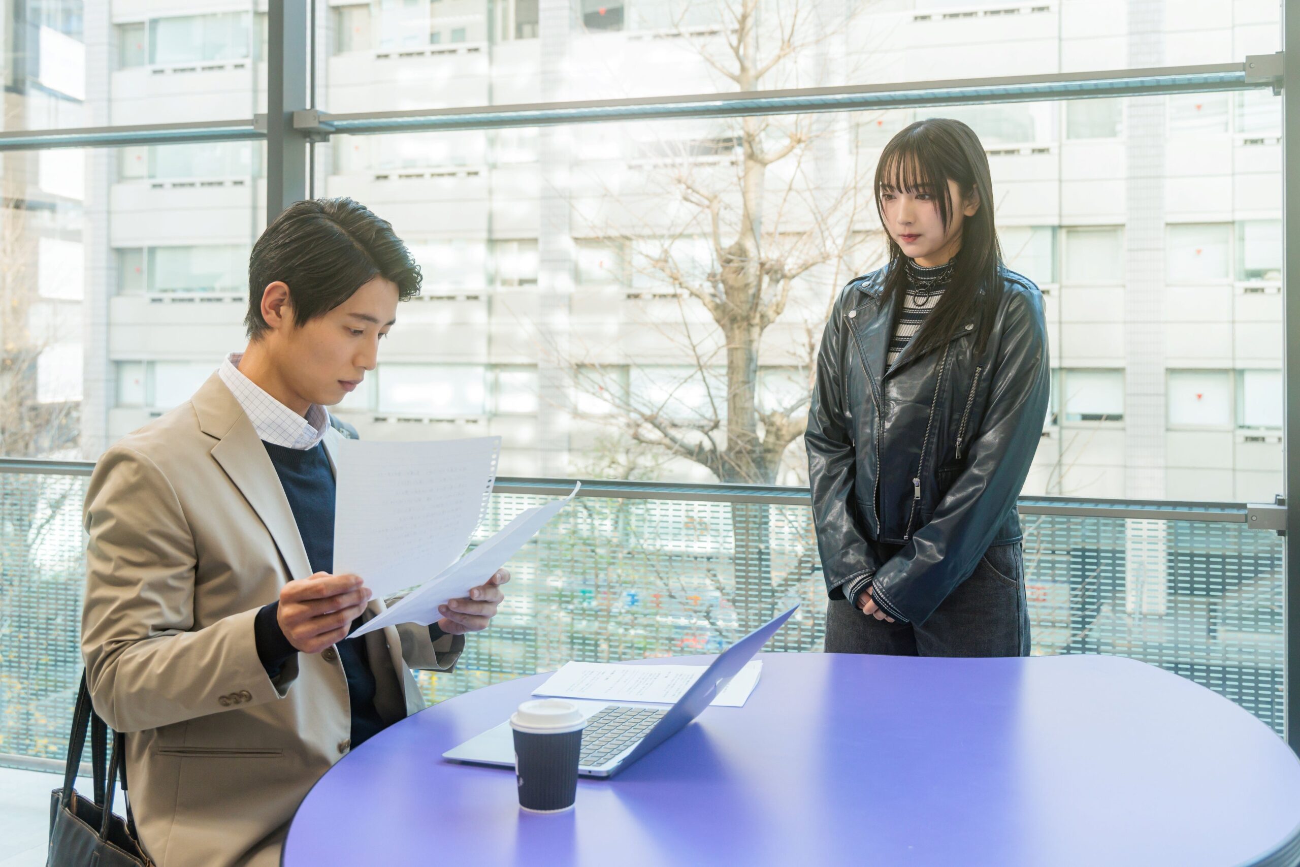 室内で書類を見る男性と立つ女性