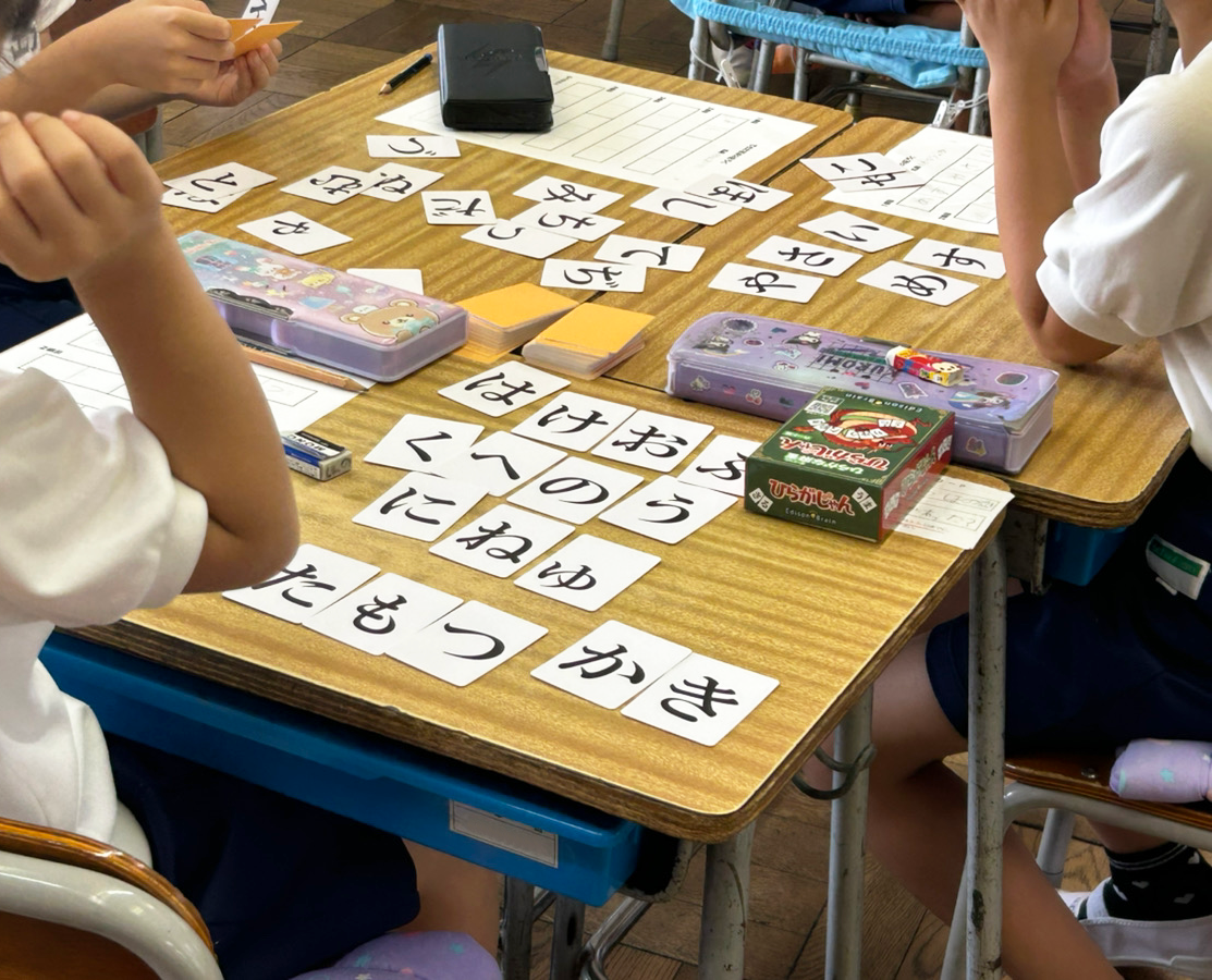 机上に広がるひらがなカードと文具