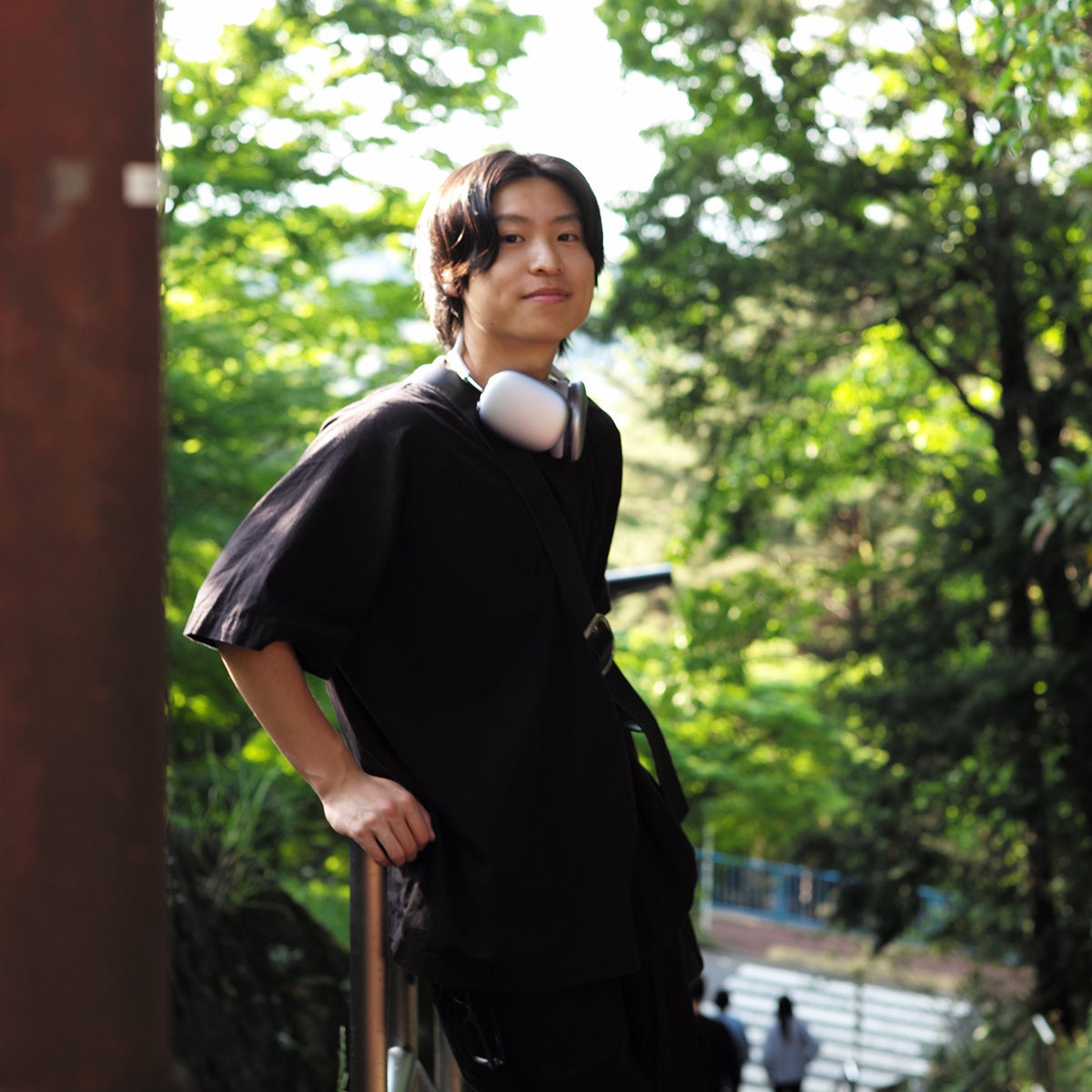 緑の背景で立つヘッドフォンの若者