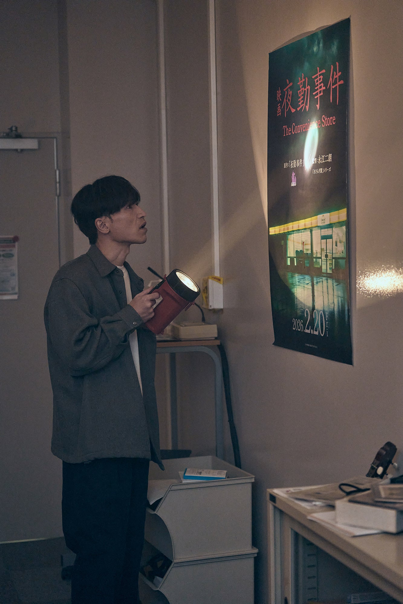 懐中電灯を持ちポスターを見る男性