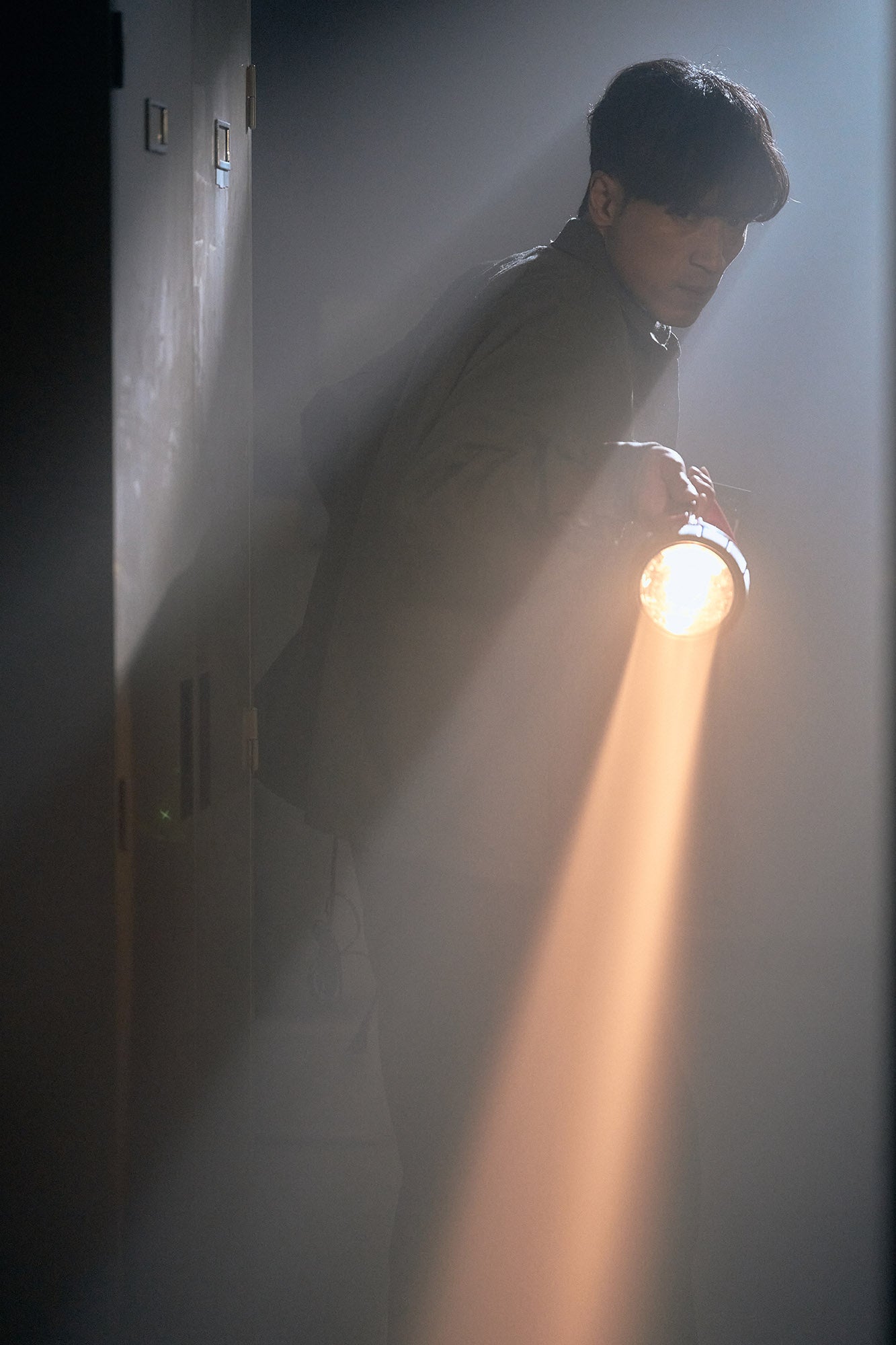 暗い廊下で懐中電灯を持つ男性