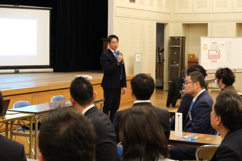 男性が聴衆の前でマイクを持つ講演