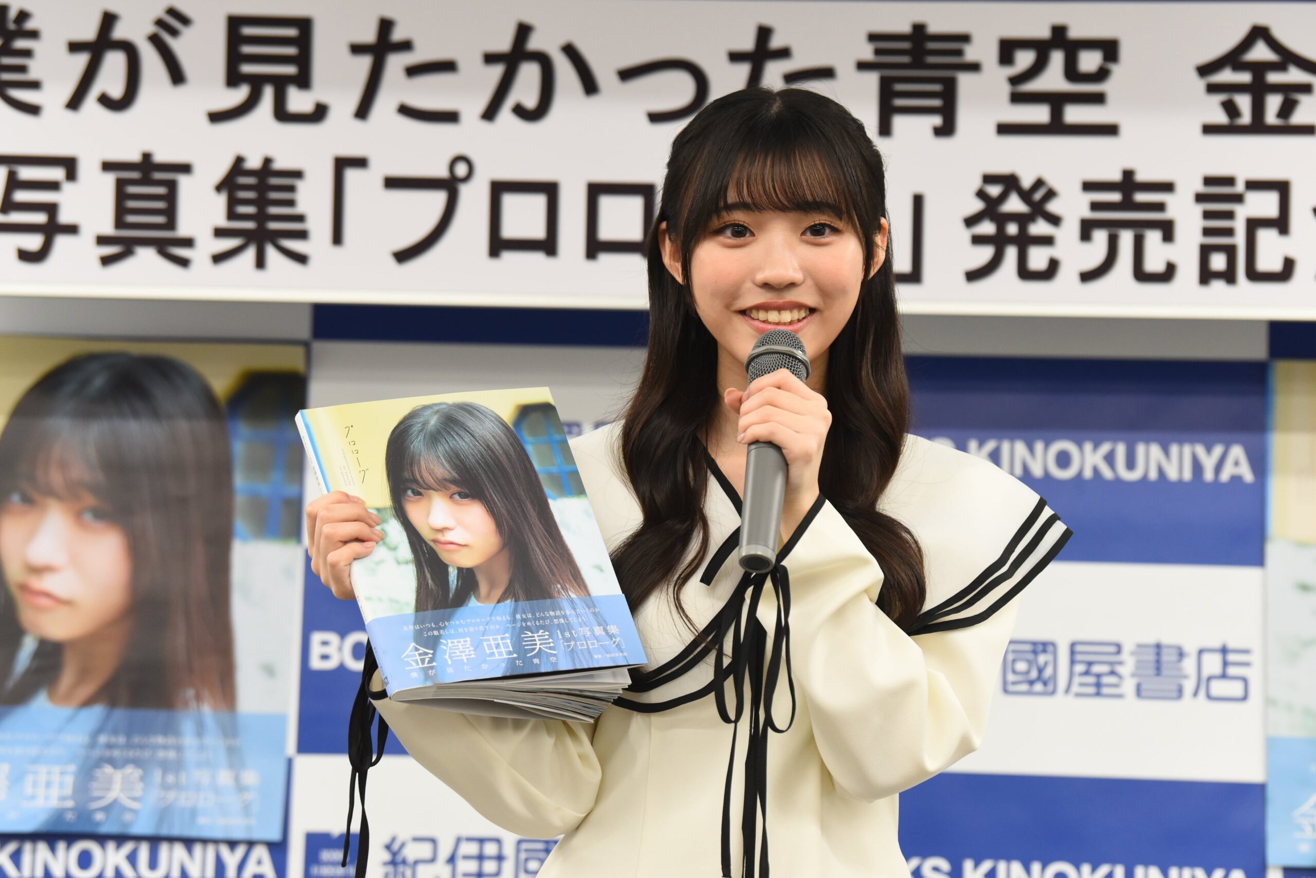 金澤亜美がマイクを持ち写真集を紹介
