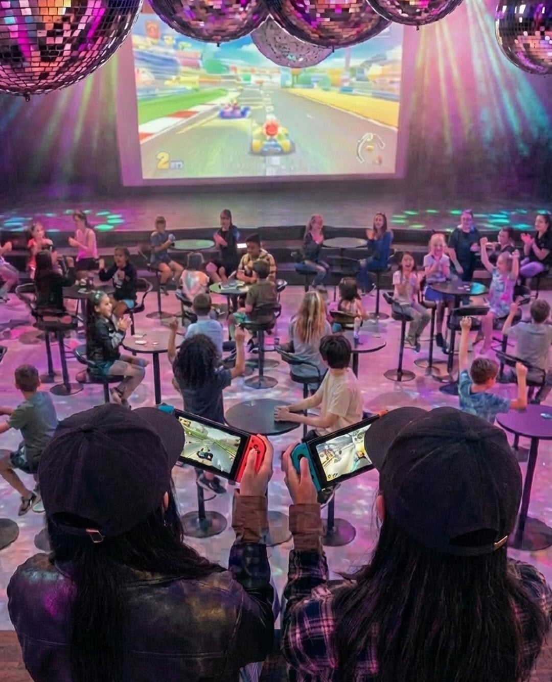大スクリーンでマリオカートを競う子どもたち