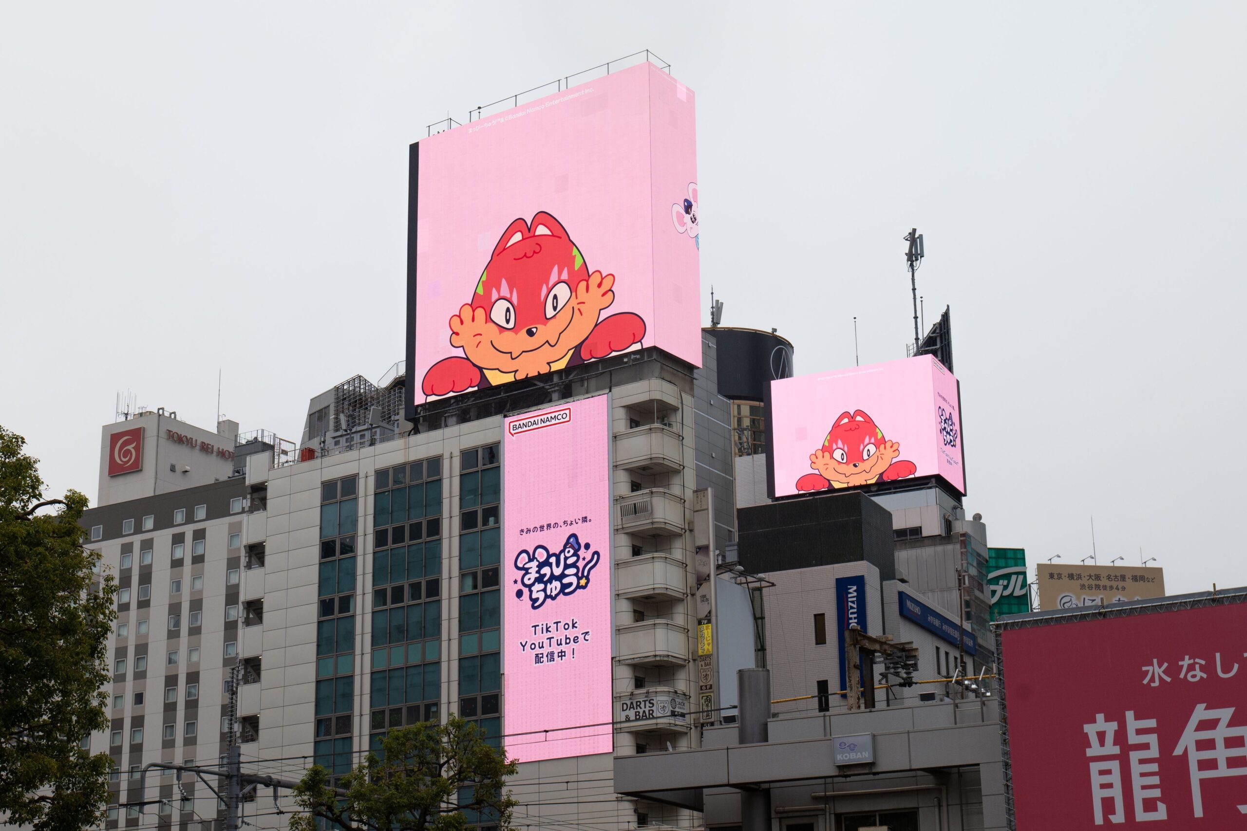 ピンクの背景にキャラクターが映る大型スクリーン