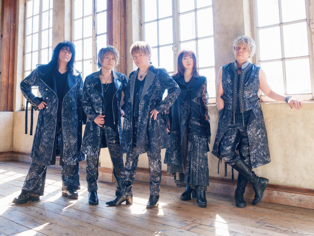 窓際でポーズを取るJAM Projectのメンバー