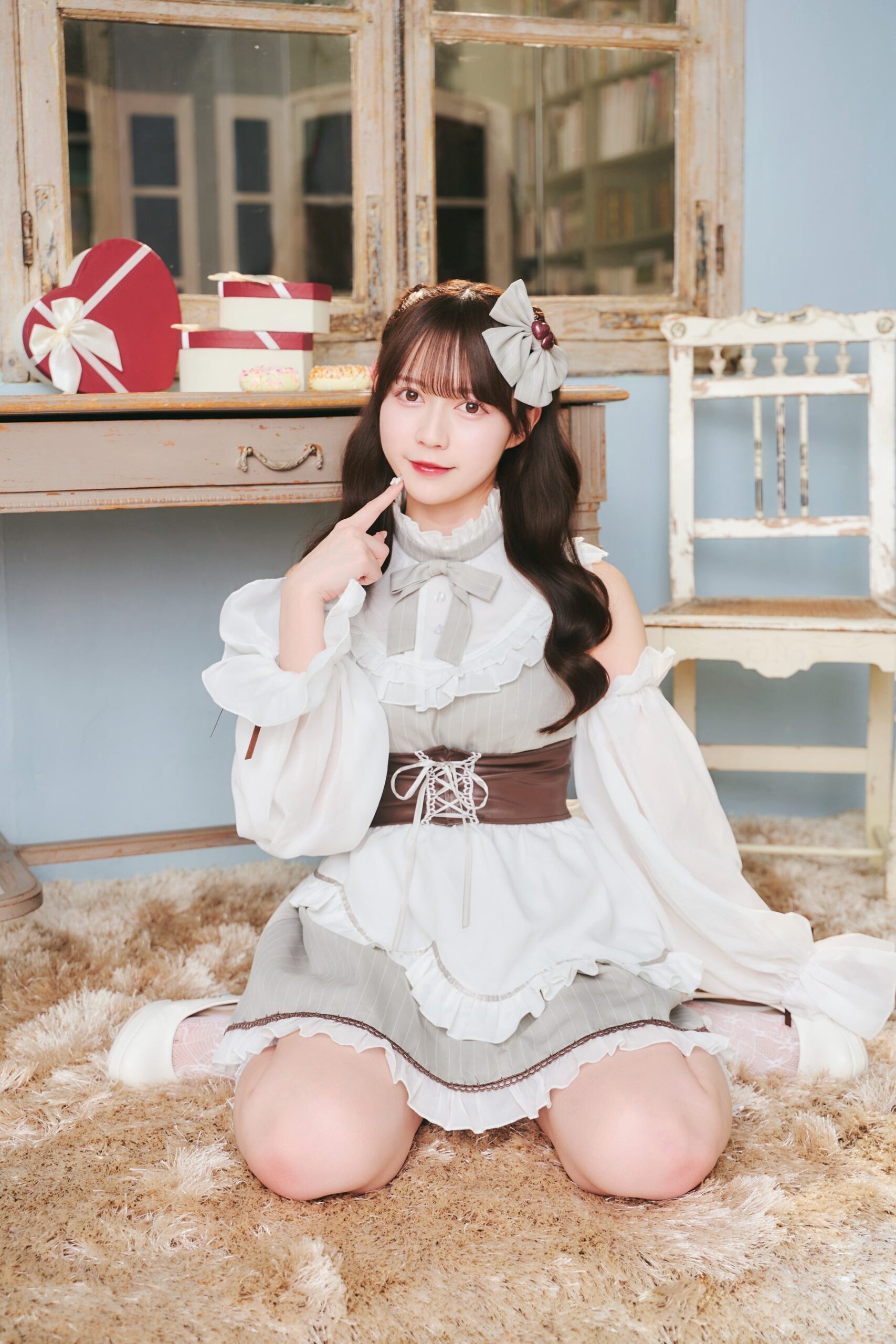 机の前でポーズを取るメイド服の女性